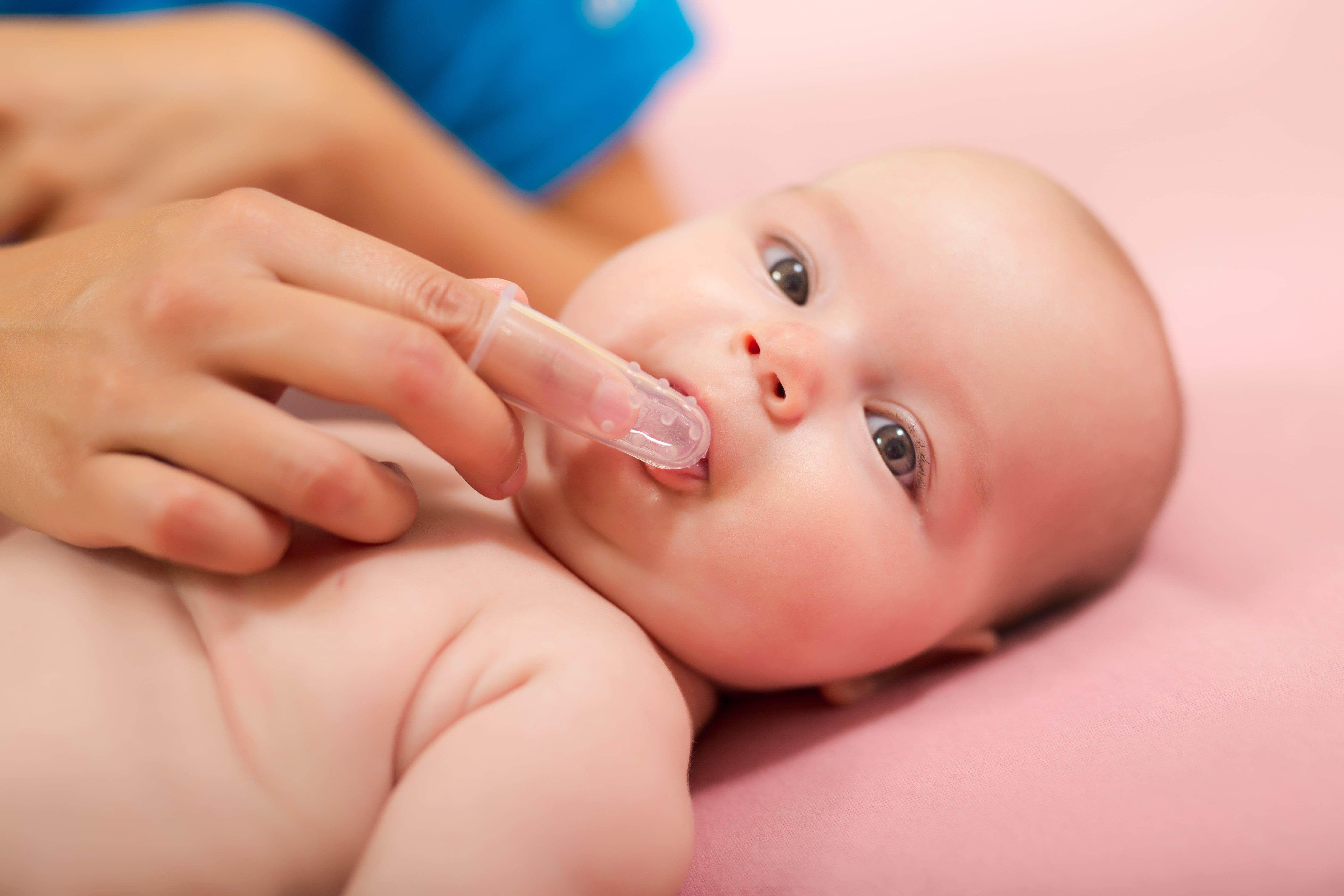 Baby having their gums gently cleaned with a finger brush