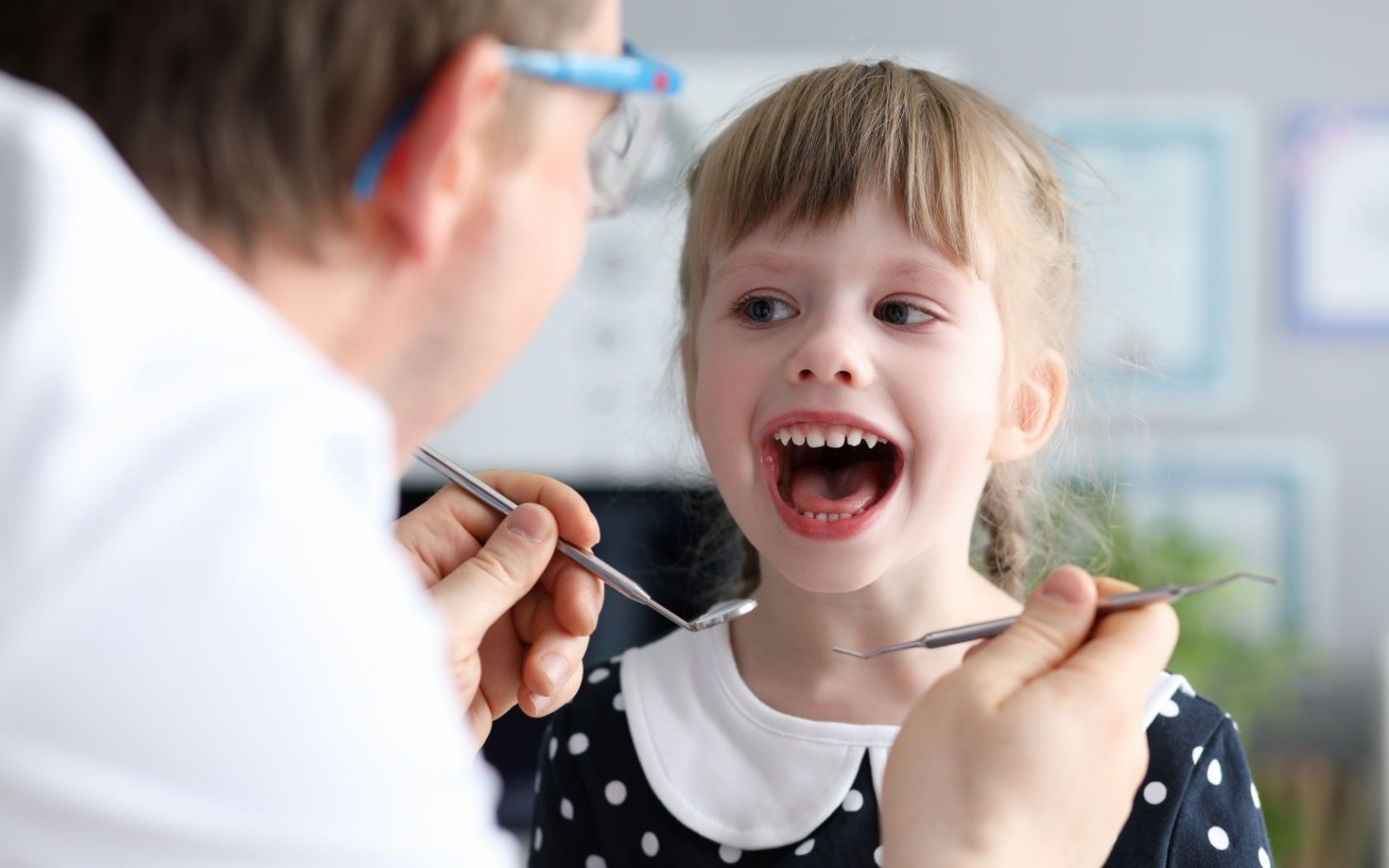 Child Smiling While Getting Checkup At Dentist