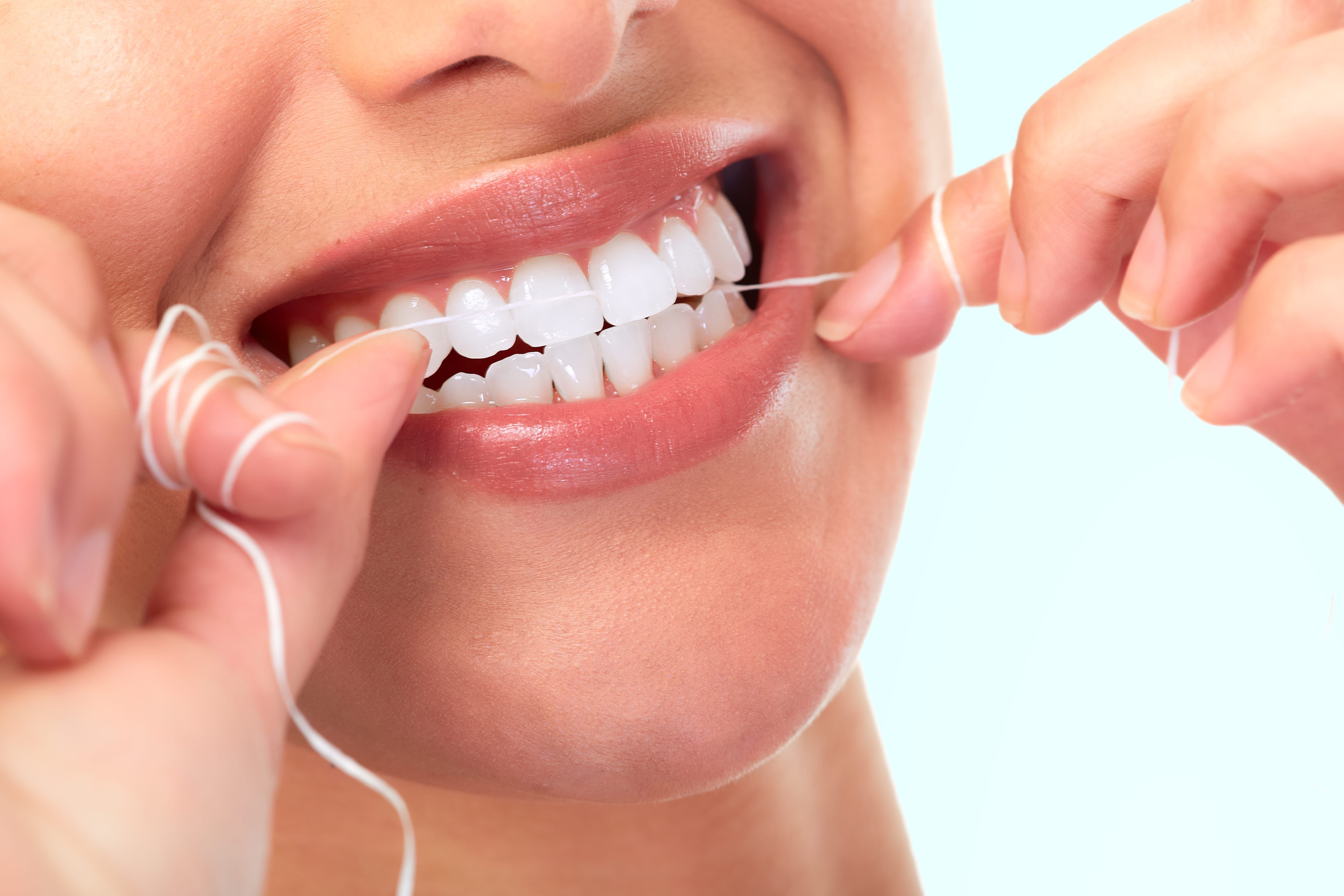 Close up image of a woman flossing her teeth