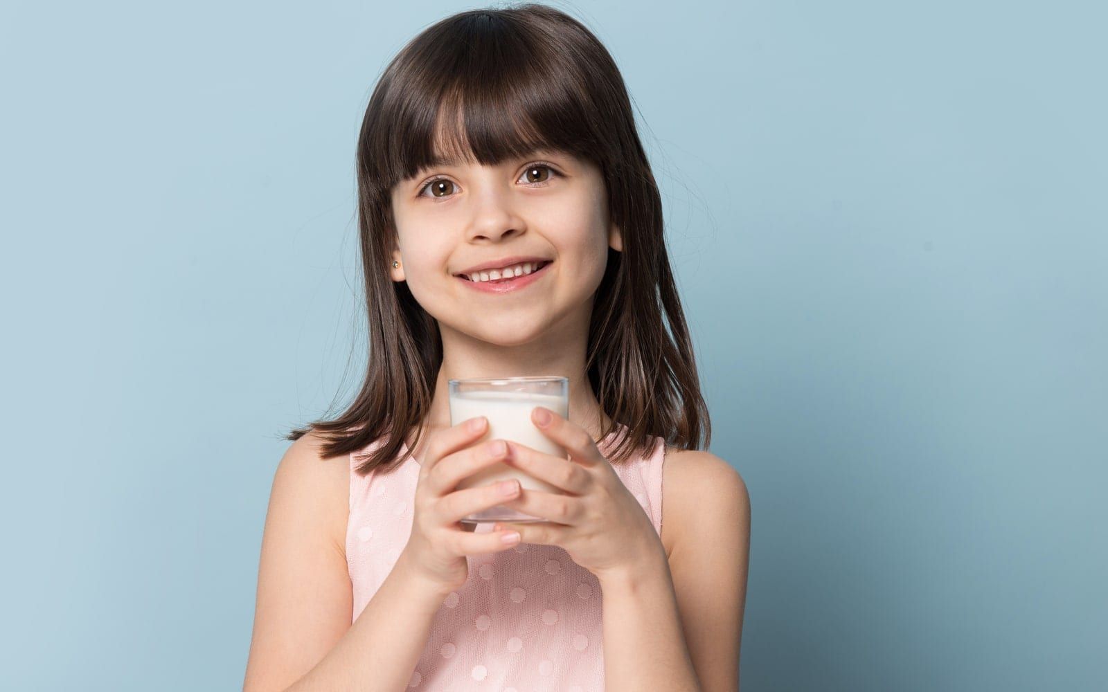 Child holding glass of milk and smiling