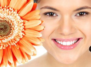Woman smiling next to a giant orange flower