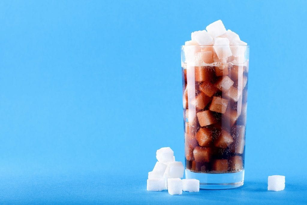 cup of soda filled with sugar cubes