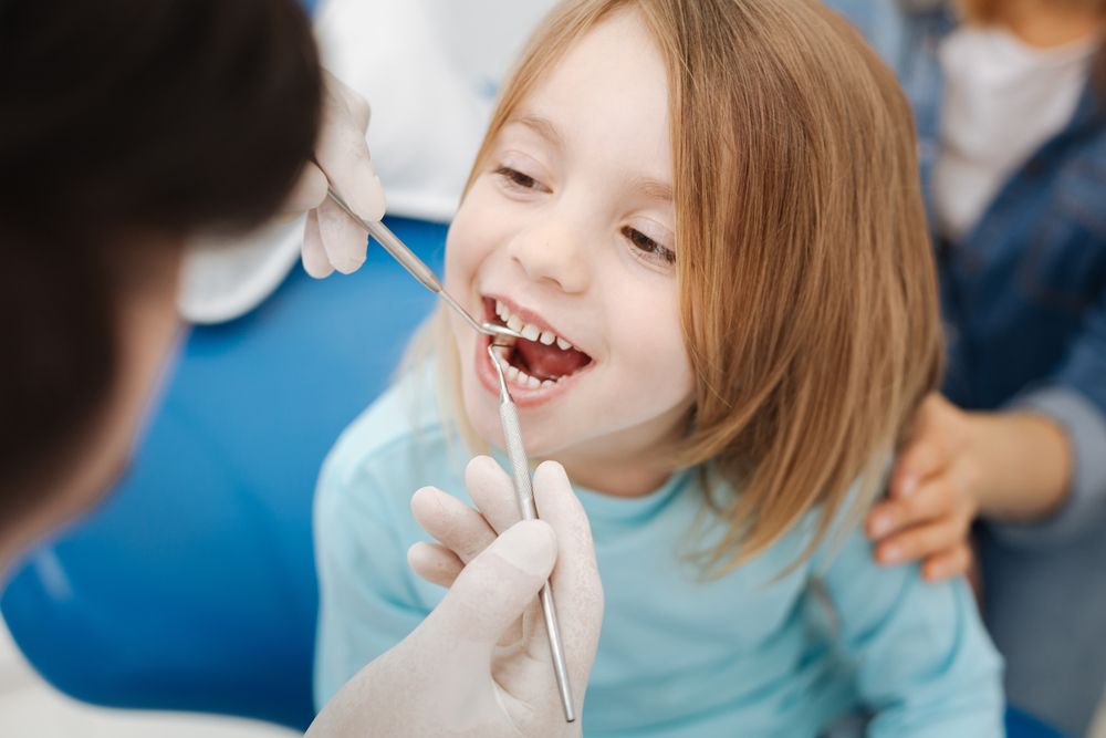 Special needs child smiling as the doctor checks her teeth with instruments