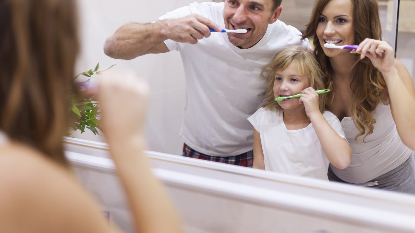 Adult and child brushing teeth